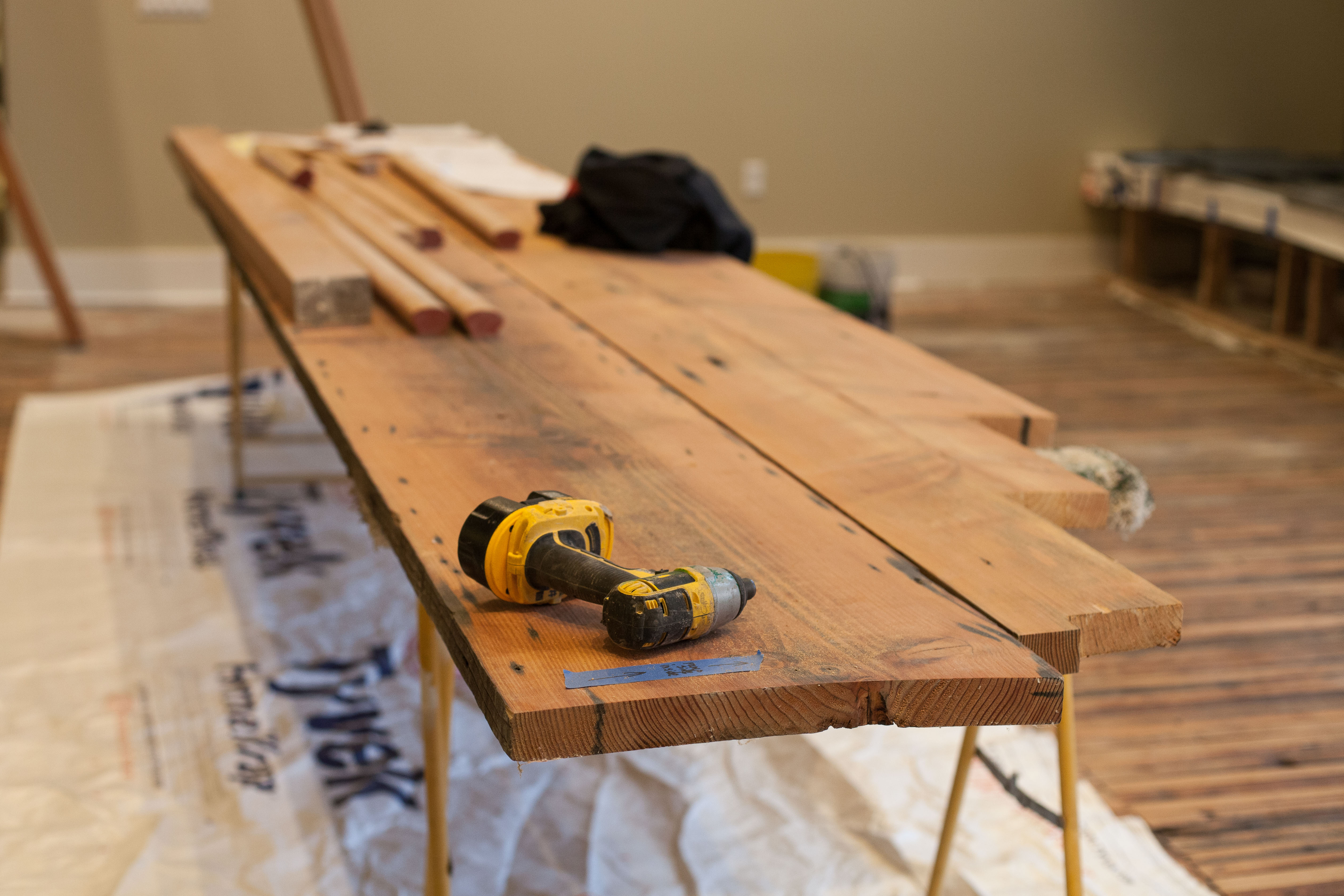 A power tool lays momentarily idle on a reclaimed wood piece awaiting installation.